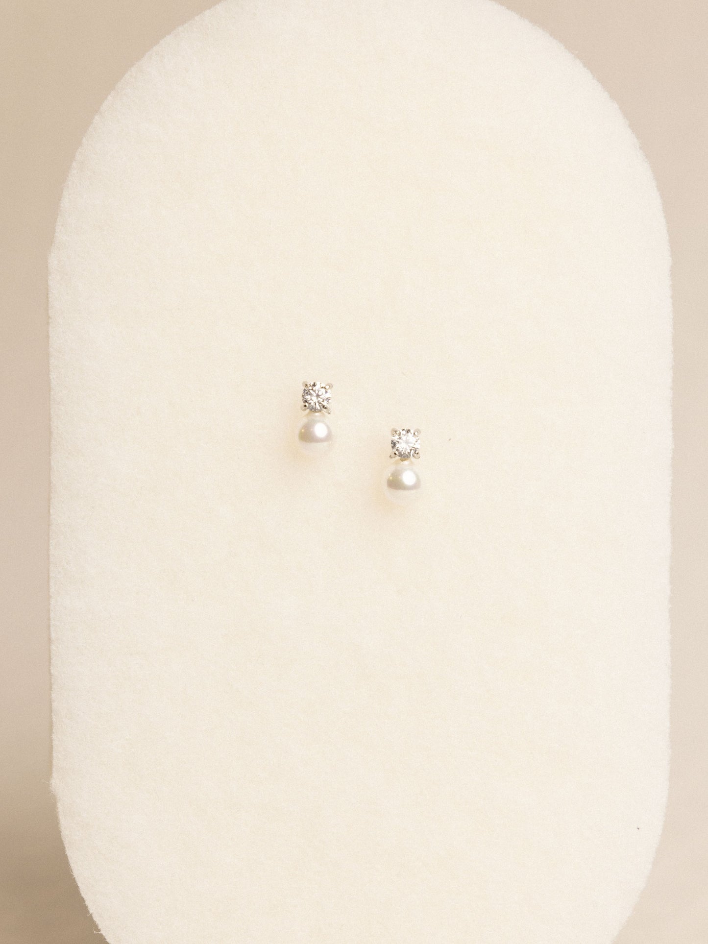 Pair of pearl earrings on a beige background