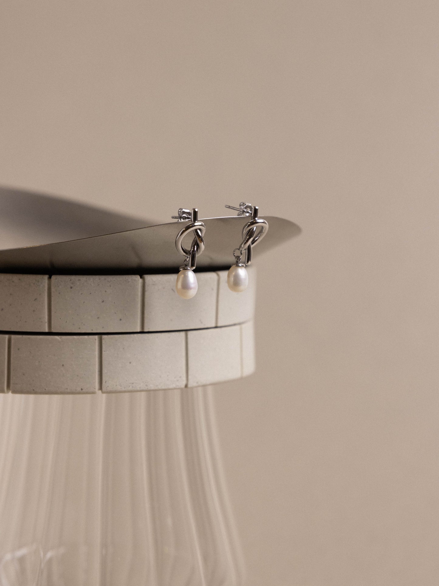 Silver earrings with pearl drops on a beige background