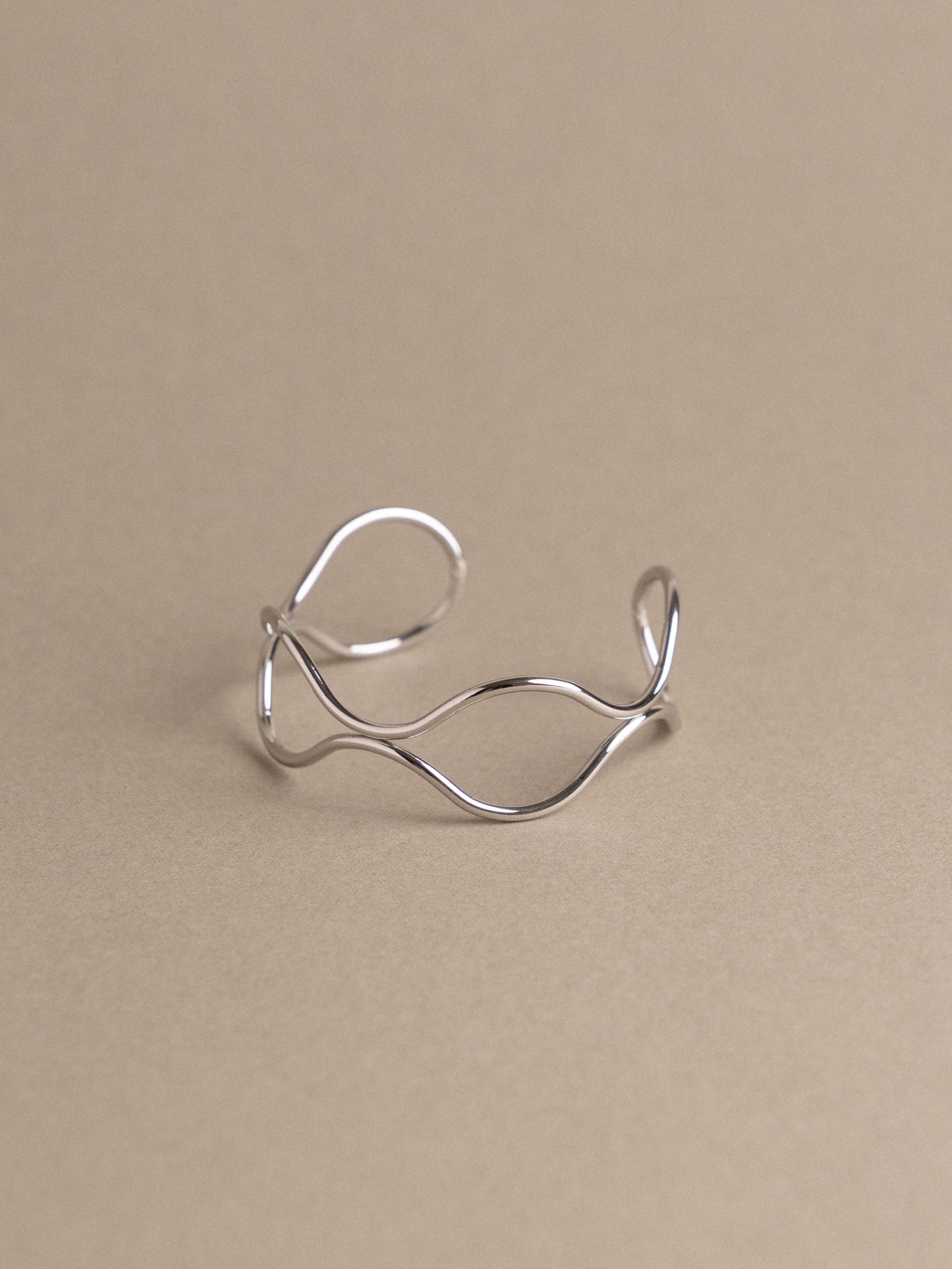 Silver open ring on a beige background