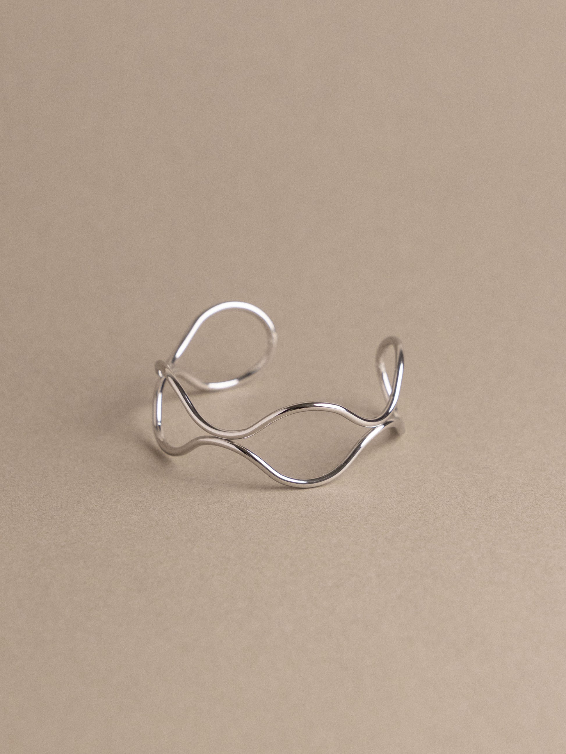 Silver open ring on a beige background
