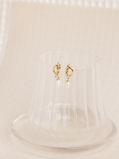 Gold hoop earrings on a clear stand with a beige background