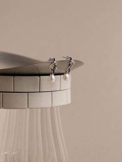 Silver earrings with pearl drops on a beige background