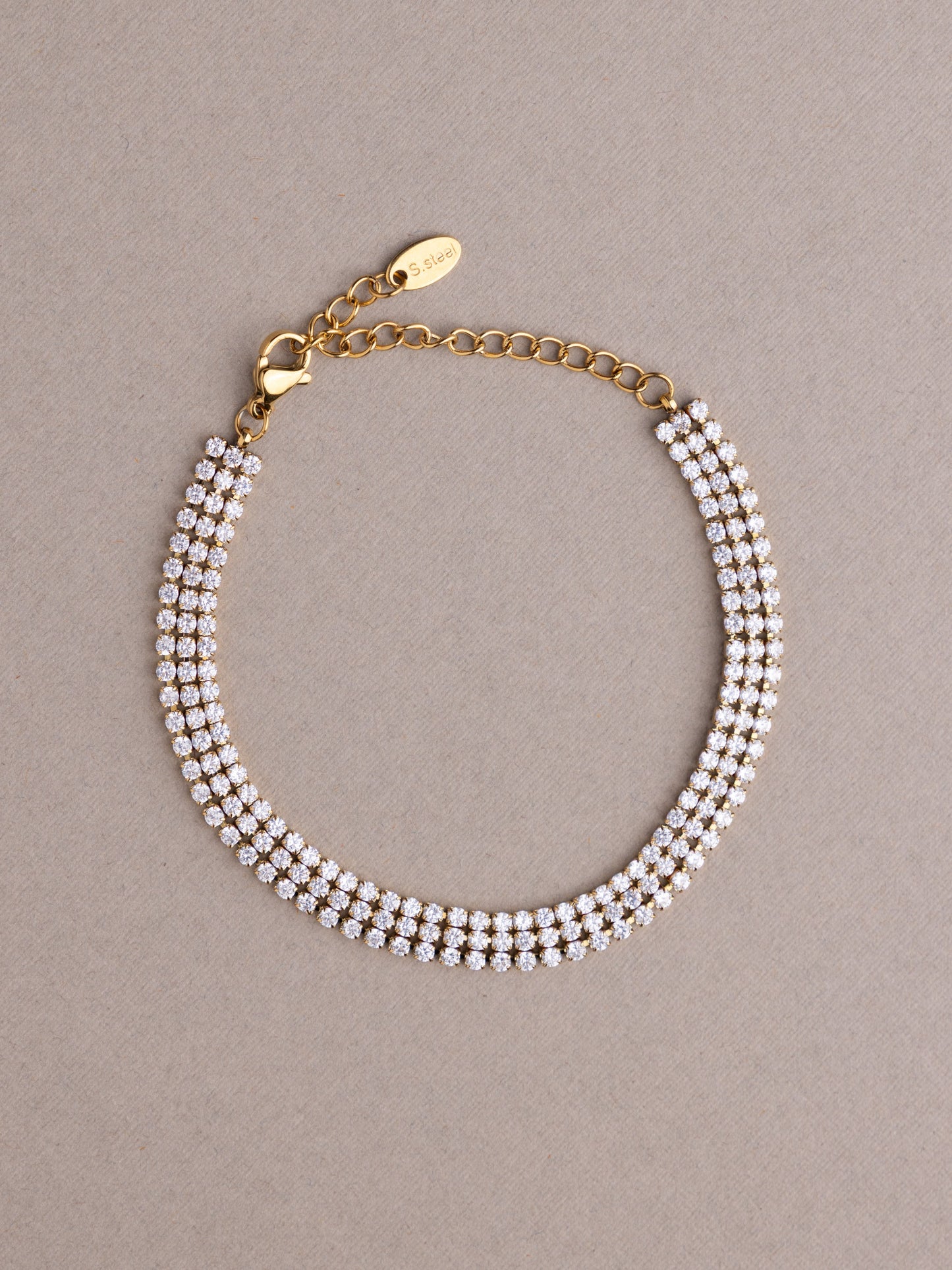Gold bracelet with pearl-like beads on a beige background