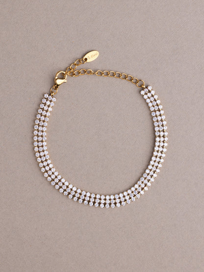 Gold bracelet with pearl-like beads on a beige background