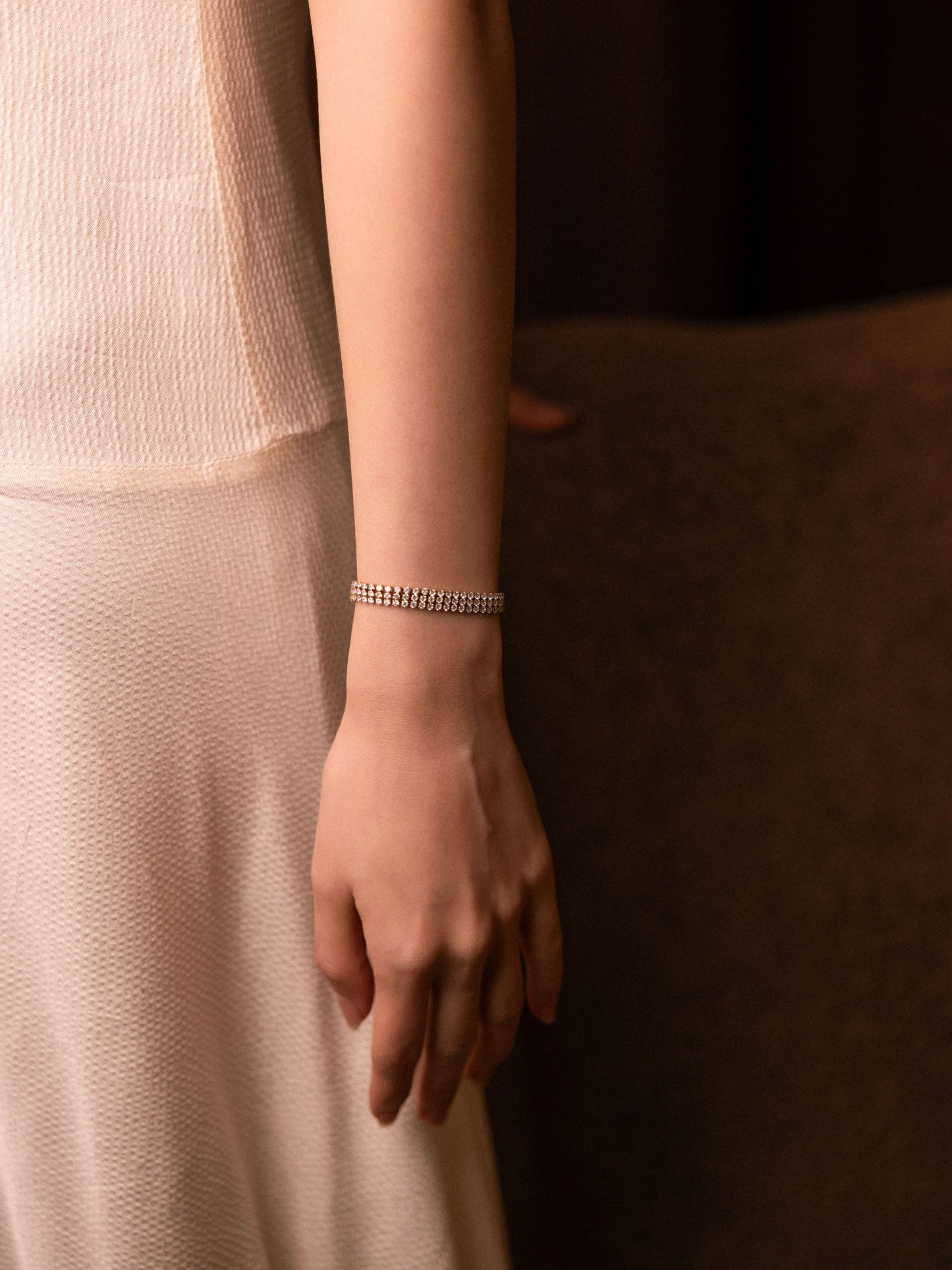 Close-up of a person wearing a silver bracelet on a neutral background