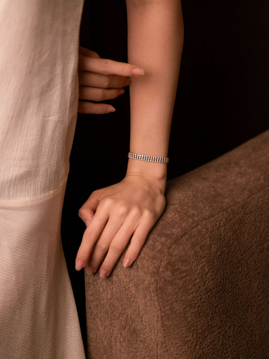 Person wearing a silver bracelet on a dark background